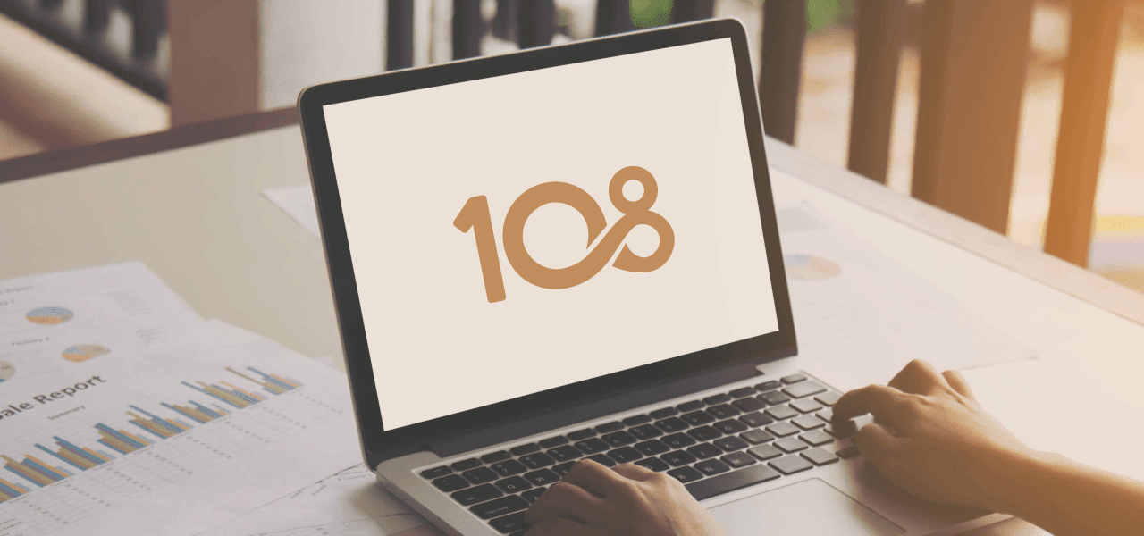 A laptop displaying the 108 Capital logo on a desk with business reports — reflecting 108 Capital's focus on digital-first businesses